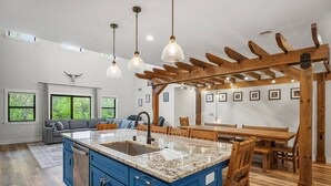Cozinha ampla com armários azuis, bancada de granito e pérgola de madeira.