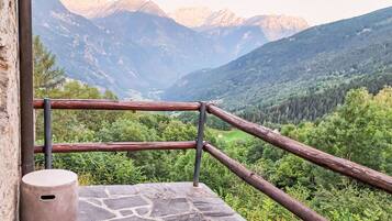 A stone ledge with a rustic railing overlooking a mountainous landscape.