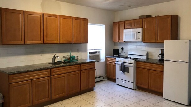 A kitchen with wooden cabinets, a stove, a microwave, and a refrigerator. - 3,000 sf loft-style floor of a historic building, sleeps 8, NYC train 5-min walk (Elizabeth)