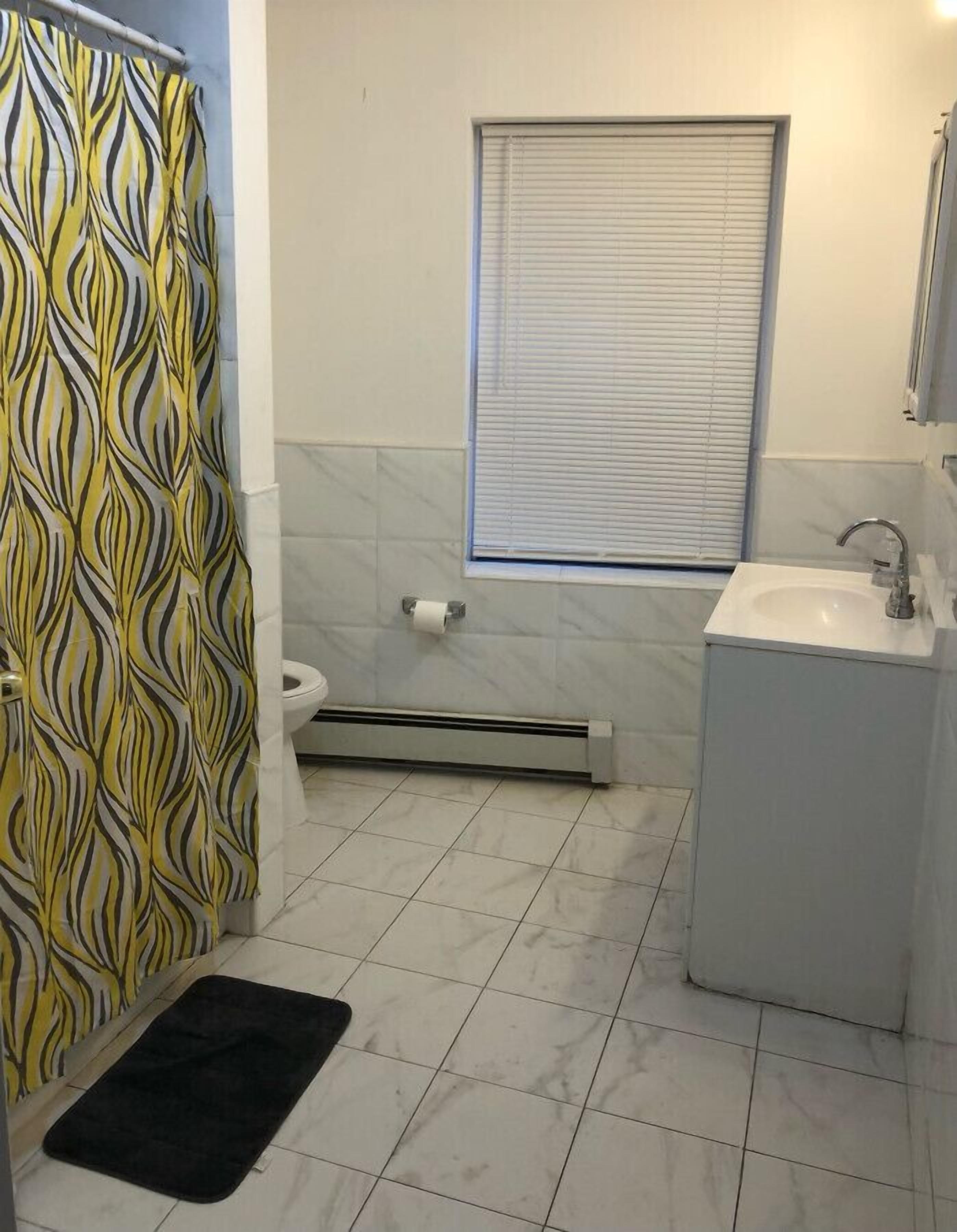 Une salle de bain avec des toilettes, une fenêtre, un lavabo et un rideau de douche.
