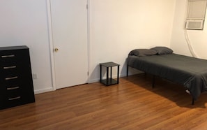 A room with a bed, a small table, a wardrobe, and a door. - 3,000 sf loft-style floor of a historic building, sleeps 8, NYC train 5-min walk (Elizabeth)