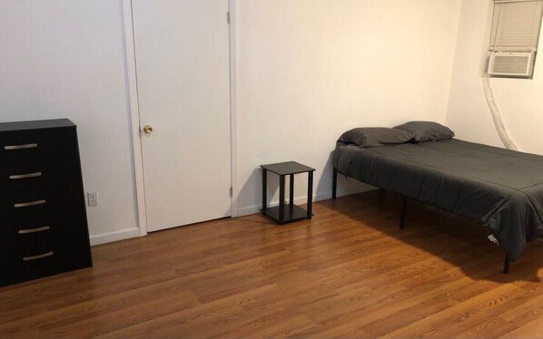 A room with a bed, a small table, a wardrobe, and a door.