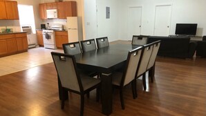 A modern kitchen with wooden cabinets, a dining table with chairs, and a flat-screen TV. - 3,000 sf loft-style floor of a historic building, sleeps 8, NYC train 5-min walk (Elizabeth)