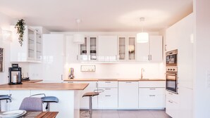 Una cocina moderna con armarios blancos, encimera de madera y electrodomésticos de acero inoxidable.