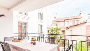 Un balcón con mesa y sillas, con vista a una zona residencial con edificios y vegetación.