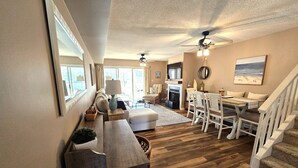 A spacious living room with a fireplace, a dining area with white chairs, and a staircase. - Lovely Mallard Lakes townhome, minutes from Fenwick and OC beaches. (Selbyville)