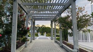 A wooden pergola structure with a paved pathway leading to a gate. - Lovely Mallard Lakes townhome, minutes from Fenwick and OC beaches. (Selbyville)