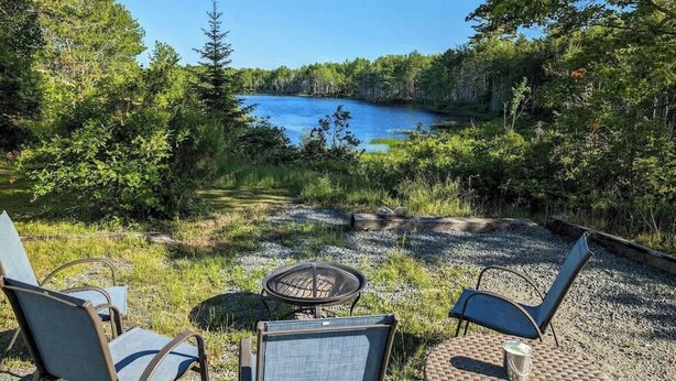 A patio with outdoor seating and a view of a lake surrounded by trees.
