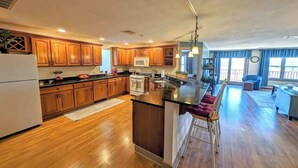 A spacious kitchen with wooden cabinets, a central island, and a dining area with a bar stool.