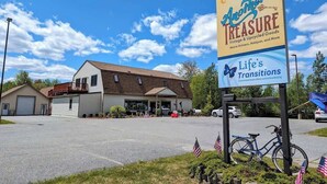 A building with a garage, a covered porch, and a sign for Anohar's Treasure.
