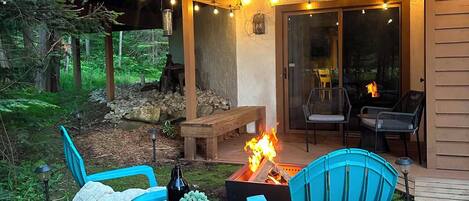 Un área de estar al aire libre con techo, sillas, una chimenea y guirnaldas de luces.