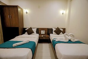 A hotel room with two beds, a wardrobe, a nightstand, and wall-mounted lights. - Hotel A1 Plaza - Ahmedabad (Ahmedabad)