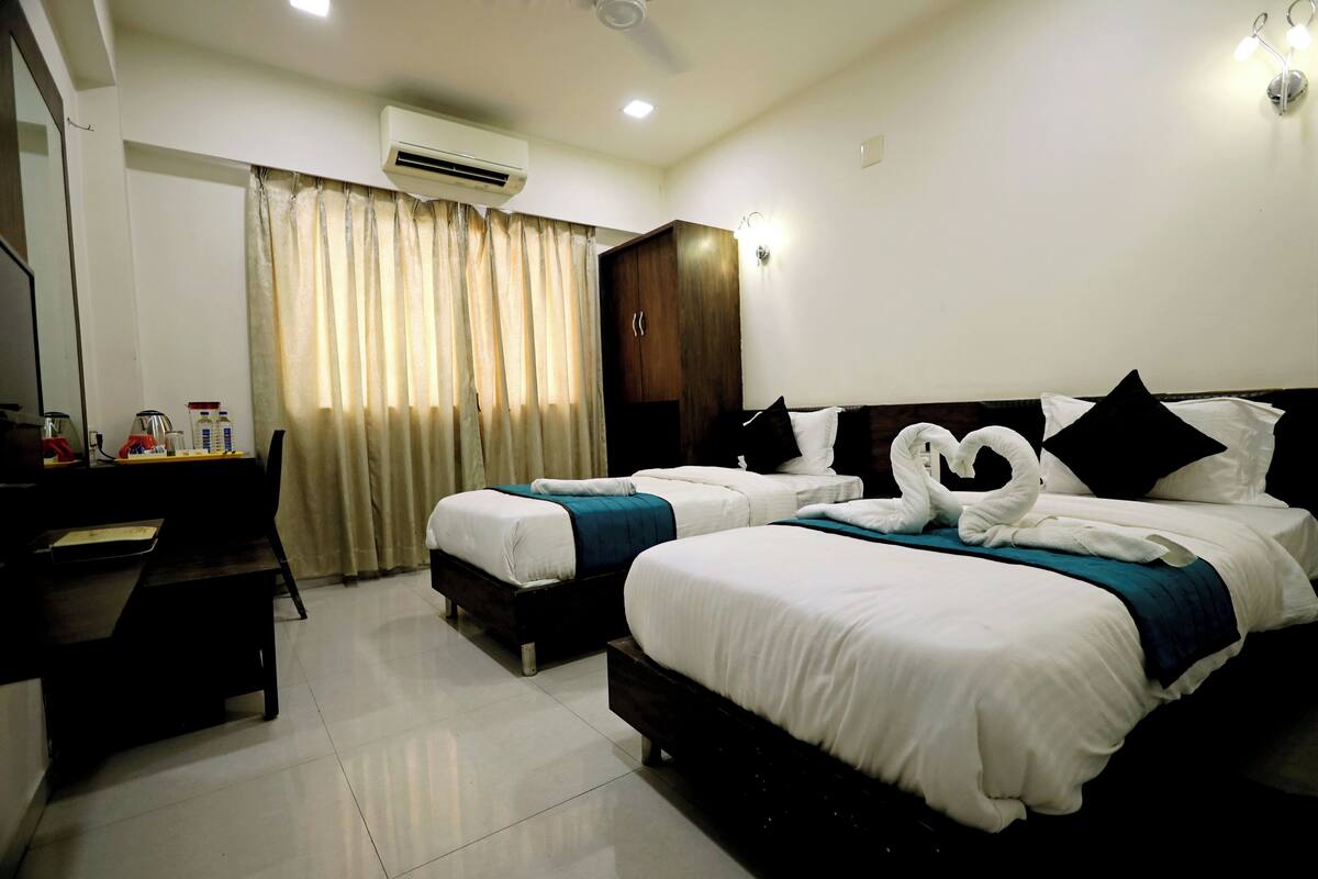 A hotel room with two beds, a desk, a wardrobe, and a curtain.