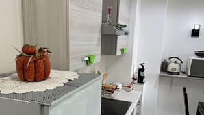 Une cuisine moderne équipée d’un réfrigérateur, d’une cuisinière et d’un évier. On peut voir une citrouille décorative posée sur le plan de travail.