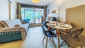 Una sala de estar moderna con sofá, mesa de comedor, sillas y una zona de cocina con cafetera.