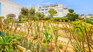 Edificio residencial con varios balcones y un jardín con diversas plantas.