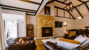 A cozy living room with a stone fireplace, leather sofas, and a dining area with wooden furniture.