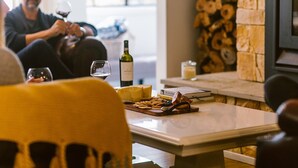 A cozy indoor setting with a table set for a meal, including cheese and bread, and a bottle of wine.