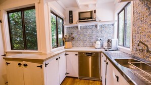 A compact kitchen with white cabinets, a stainless steel dishwasher, a microwave, and a sink.