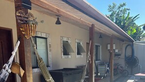 Un espacio al aire libre techado con una hamaca, un banco de madera y una bicicleta.