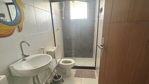 Un baño con lavamanos, inodoro y zona de ducha.