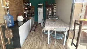 Una cocina compacta con refrigerador, pileta y mostrador. En primer plano, se observa una mesa de comedor con sillas y un alfombra rojo.