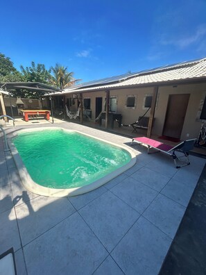 Relax by the rectangular pool surrounded by a patio with a bench and hammock.