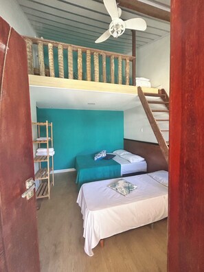 Cozy retreat with a wooden staircase, balcony, and two beds.
