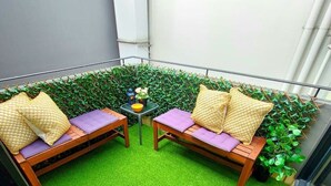 A small outdoor seating area with two wooden sofas and a table, surrounded by green artificial turf and a hedge. - Great apartment in the City / Broadway-Chippendale, Sydney (Chippendale)