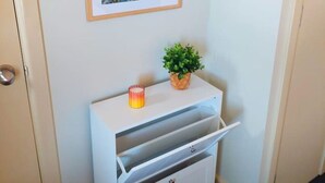 A hallway with a white cabinet, a framed sunflower picture, a small potted plant, and a candle.