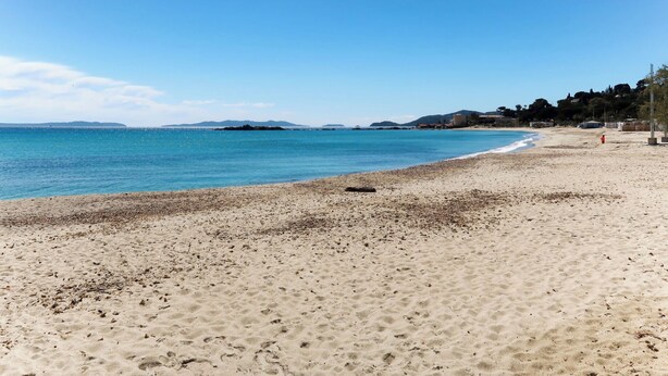 A sandy beach with clear blue water and distant hills. - Saint James by Interhome (Le Lavandou)