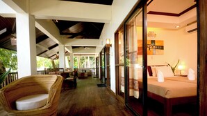 A hotel room with a bed, a wicker chair, and a view of the outdoors. - El Nido Water Front (El Nido)