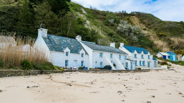 A coastal building with multiple rooms, a stone pathway leading to the entrance, and a beach in the foreground. - Hen Dafarn -  an on the beach that sleeps 5 guests  in 3 bedrooms (Nefyn)