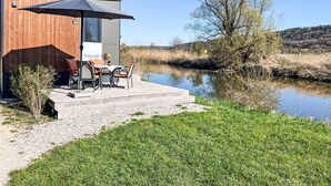 Una casa moderna con un patio que da a un río tranquilo.