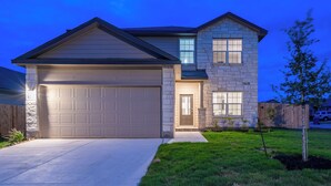 Une maison à deux étages avec un garage, une façade en pierre et une pelouse bien entretenue.