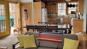A cozy living room with a sofa, a dining table, and a kitchen area with wooden cabinets and a refrigerator. - Stunning cottage on Cayuga Lake, near wineries, waterfalls, Cornell University  (Interlaken)