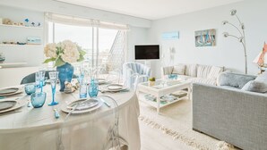 Un salón luminoso con comedor, televisor y decoración náutica.