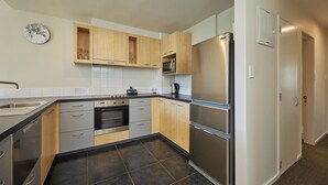 A modern kitchen with wooden cabinets, stainless steel appliances, and a tiled backsplash. - Kaikoura Luxury Apartments (Kaikoura)