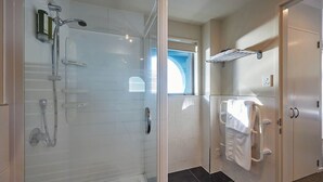 A modern bathroom with a glass-enclosed shower, a white bathtub, and a towel rack. - Kaikoura Luxury Apartments (Kaikoura)