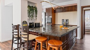 Une cuisine moderne dotée d’un grand îlot central, de meubles de rangement en bois foncé et d’une plante suspendue.
