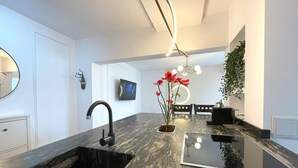 Une cuisine moderne dotée d’un plan de travail en marbre noir, d’un évier noir et d’un coin repas avec une table et des chaises.