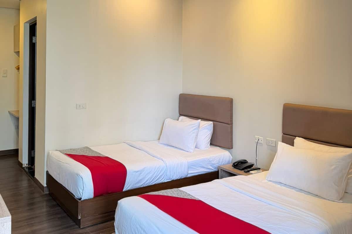 A hotel room with two beds, a wooden floor, and a modern design.