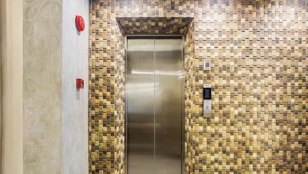 Un ascensor con una pared estampada y una puerta metálica.