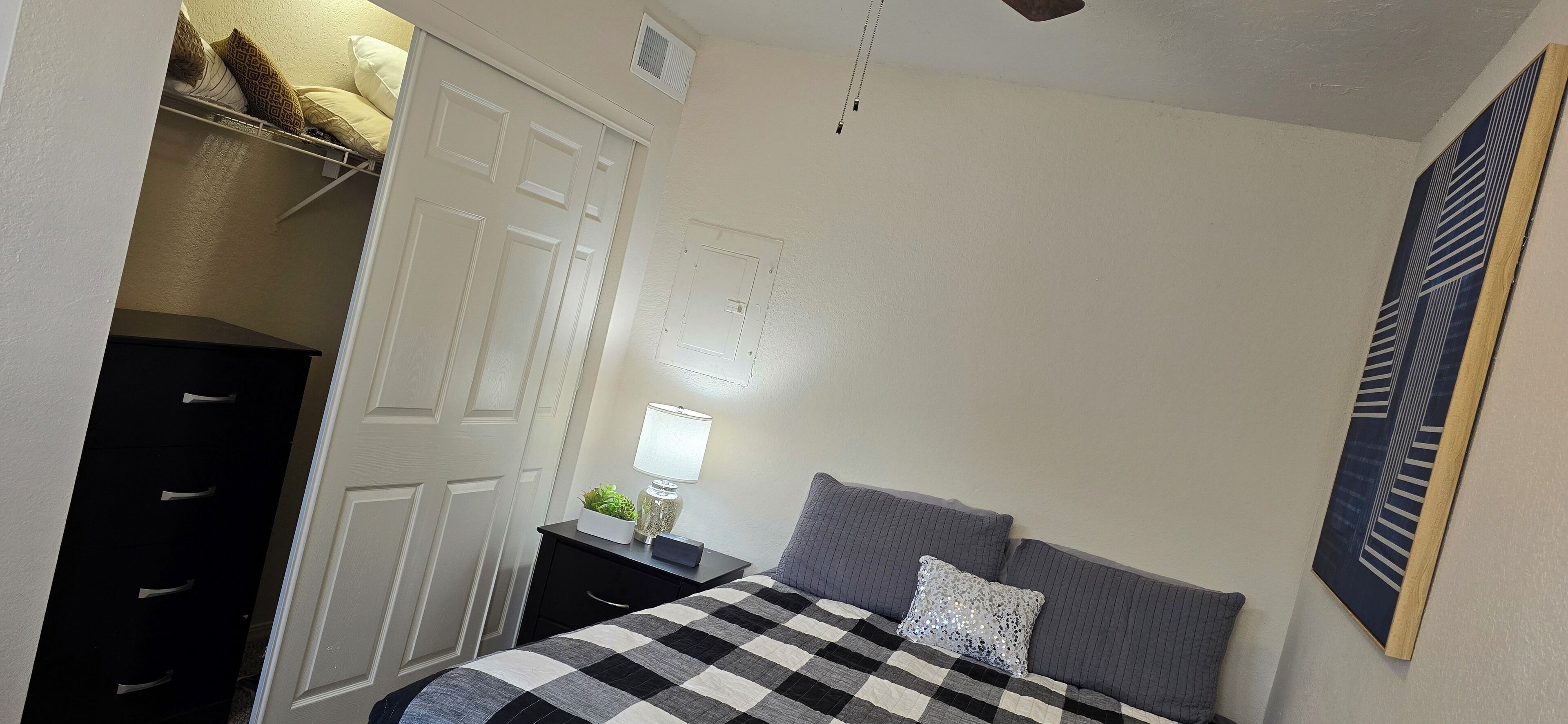 Une chambre à coucher comprenant un lit, une table de chevet, une commode et un placard.