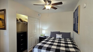 A bedroom with a checkered bedspread, a ceiling fan, a nightstand with a lamp, and a closet with a mirror. - Cozy Updated Cove of Heaven, 5 mins from Lake Hefner and mall. Centrally located (Oklahoma City)