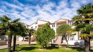 A residential building with a garden, palm trees, and a clear blue sky. - Apartment Palms by Interhome (Opatija/Pobri)