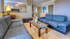 A living room with a sofa, a coffee table, and a lamp. There is a mirror on the wall and a painting above the sofa. - Apartment Palms by Interhome (Opatija/Pobri)