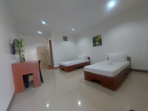 A hotel room with two beds, a desk, a chair, a wardrobe, and a painting on the wall. - RGE Hotel near Kalanggaman Island (Palompon)