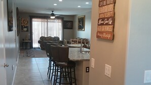 A spacious kitchen with a central island, a dining area with a sofa and chairs, and a wall with motivational signs. - Peaceful home in Estrella Mountains with beautiful lake for walking  (Goodyear)