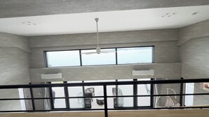 A spacious room with a large window, ceiling fan, and air conditioning unit. - Ocean view retreat! Luxury villa with sauna (本部町)